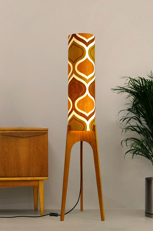 The Honey Mustard Archie Rocket Floor Lamp is a playful nod to the geometric patterns of the 1970s. Handcrafted from authentic vintage fabric and hardwood oak next to a wooden cabinet and plant.