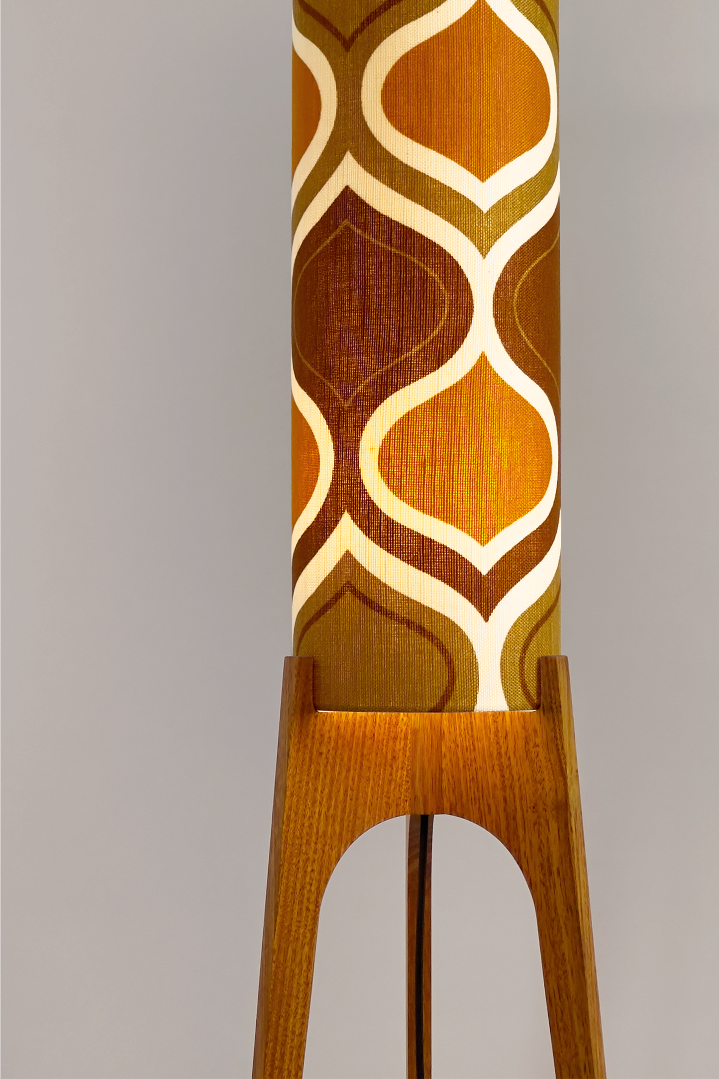 The Honey Mustard Archie Rocket Floor Lamp is a playful nod to the geometric patterns of the 1970s. Handcrafted from authentic vintage fabric and hardwood oak next to a wooden cabinet and plant.