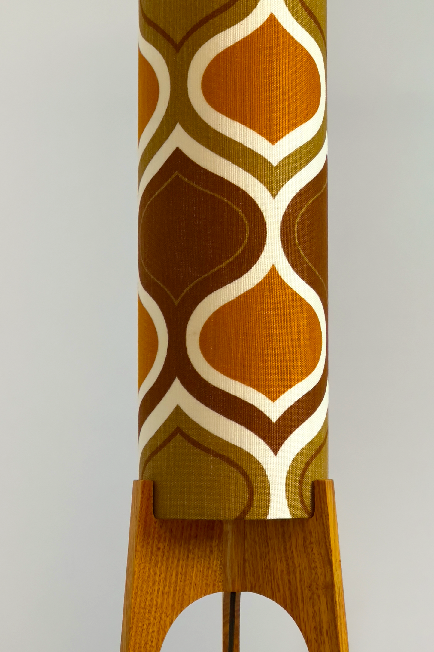 The Honey Mustard Archie Rocket Floor Lamp is a playful nod to the geometric patterns of the 1970s. Handcrafted from authentic vintage fabric and hardwood oak next to a wooden cabinet and plant.