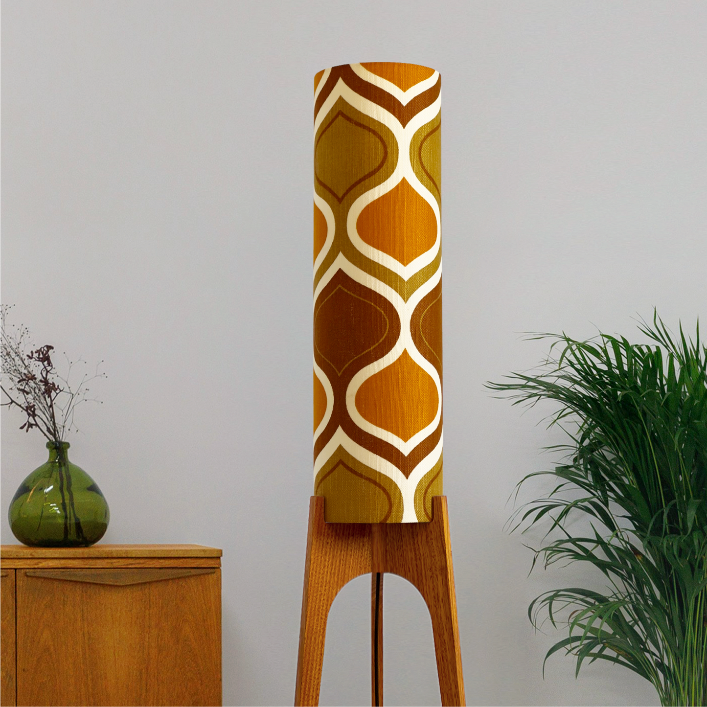 The Honey Mustard Archie Rocket Floor Lamp is a playful nod to the geometric patterns of the 1970s. Handcrafted from authentic vintage fabric and hardwood oak next to a wooden cabinet and plant.