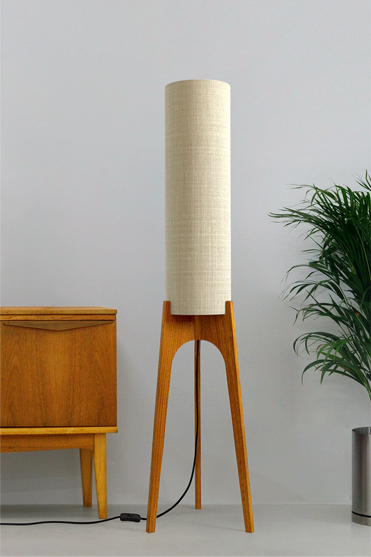 Ivory - Archie Rocket Floor Lamp handmade by Retro Duo. A soft, natural and timeless wooden floor lamp with a cylindrical shade in a room with a cabinet and a plant.