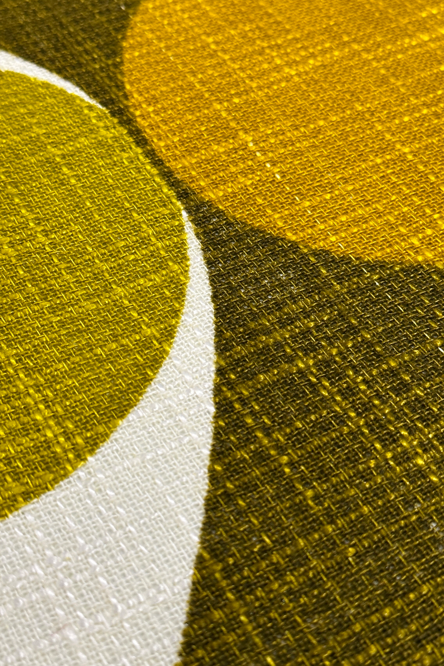 Close-up of a textured fabric with circular patterns in olive & mustard on a white background