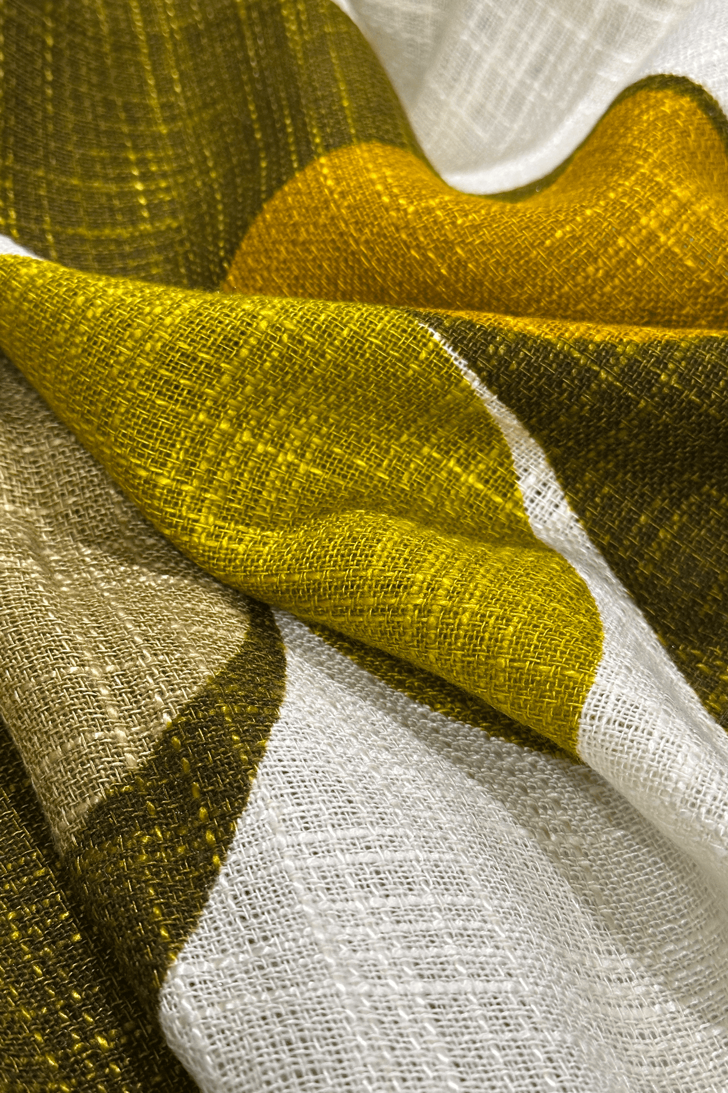 Close-up of a textured fabric with circular patterns in olive & mustard on a white background