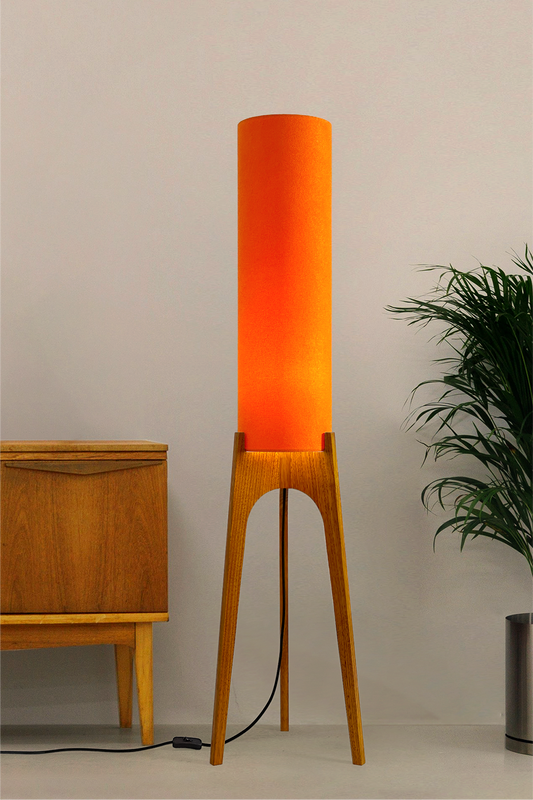 Orange - Archie Rocket Floor Lamp | Handmade by RETRO DUO with a cylindrical lampshade  and wooden lamp base next to a cabinet & plant