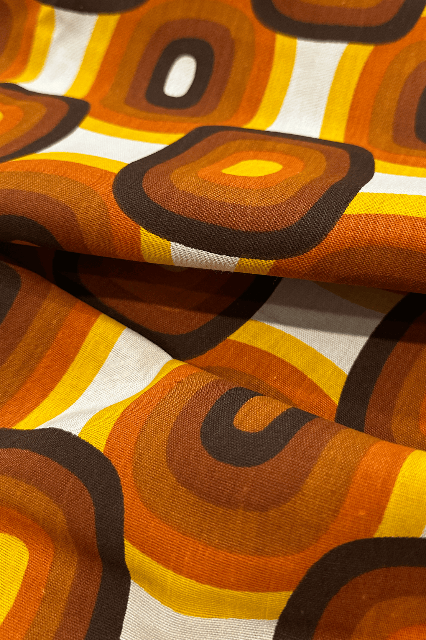 Close-up of fabric with a retro pattern featuring orange, brown, and yellow colors.