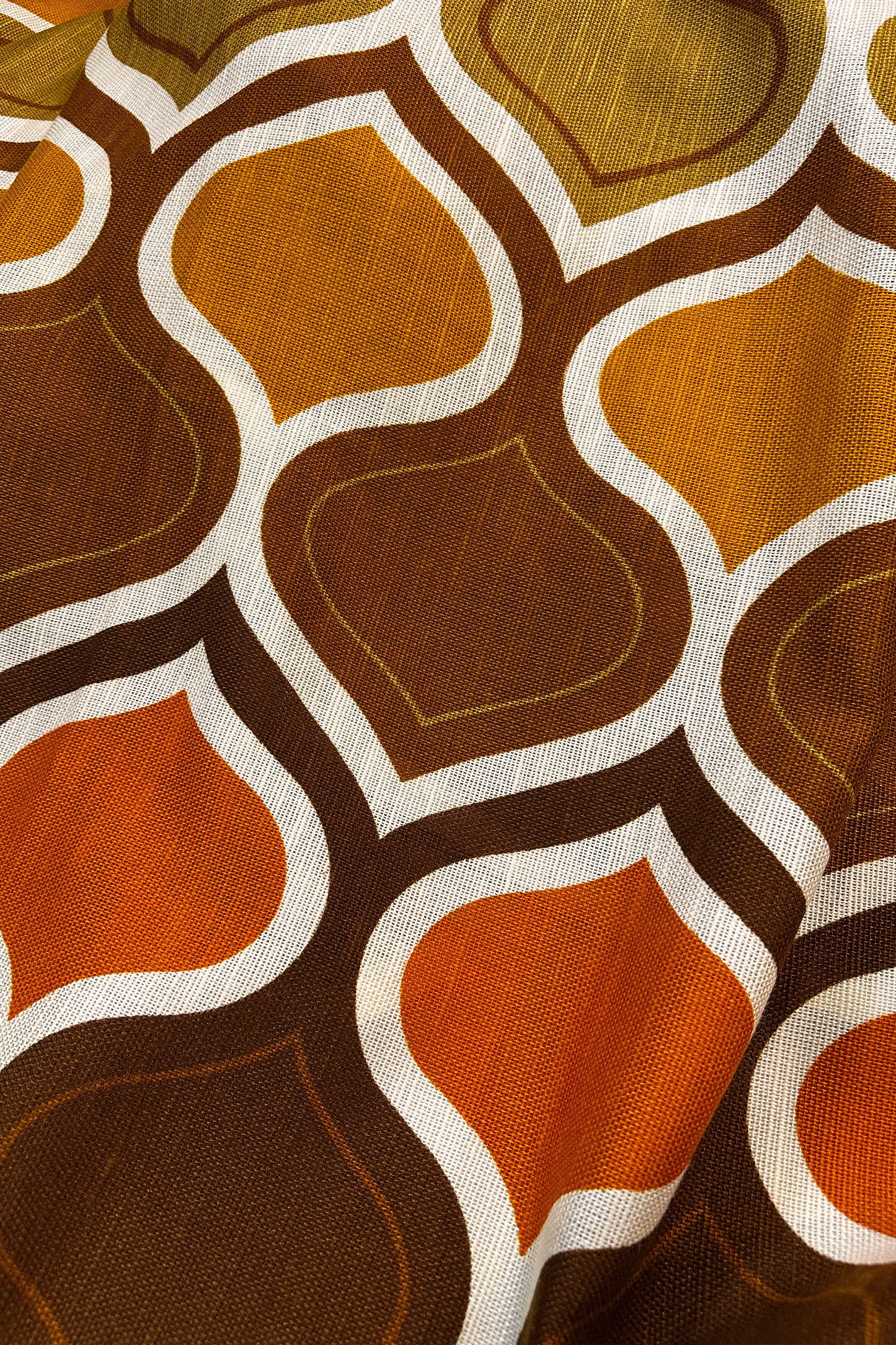 Patterned fabric with geometric design in brown, orange, and white on a black background