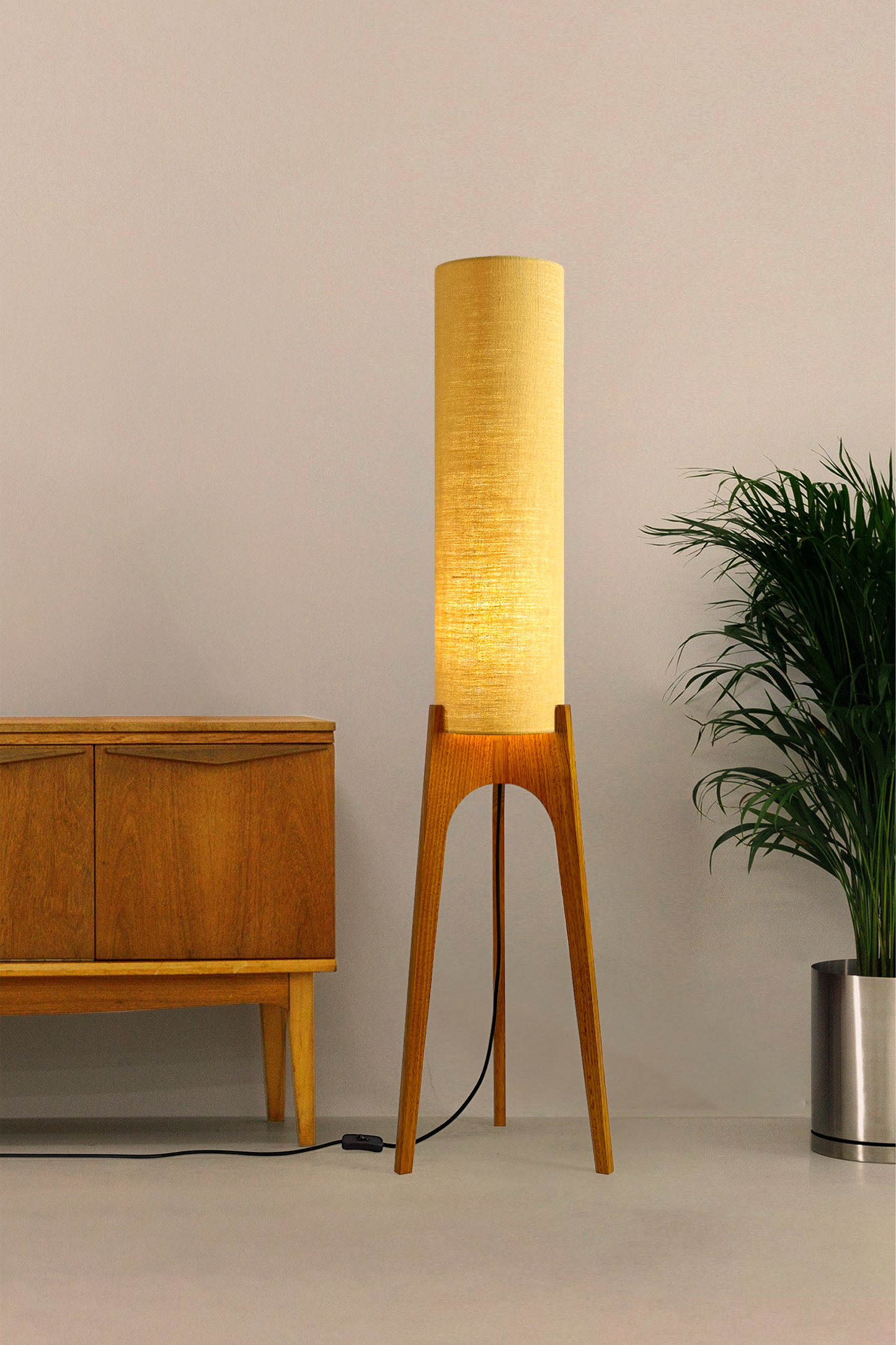 Wooden Rocket floor lamp with a premium linen shade in Wheat colour next to a wooden cabinet and plant on a beige background