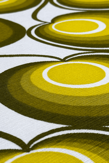 Close-up of a fabric with circular pattern in green and yellow on a white background