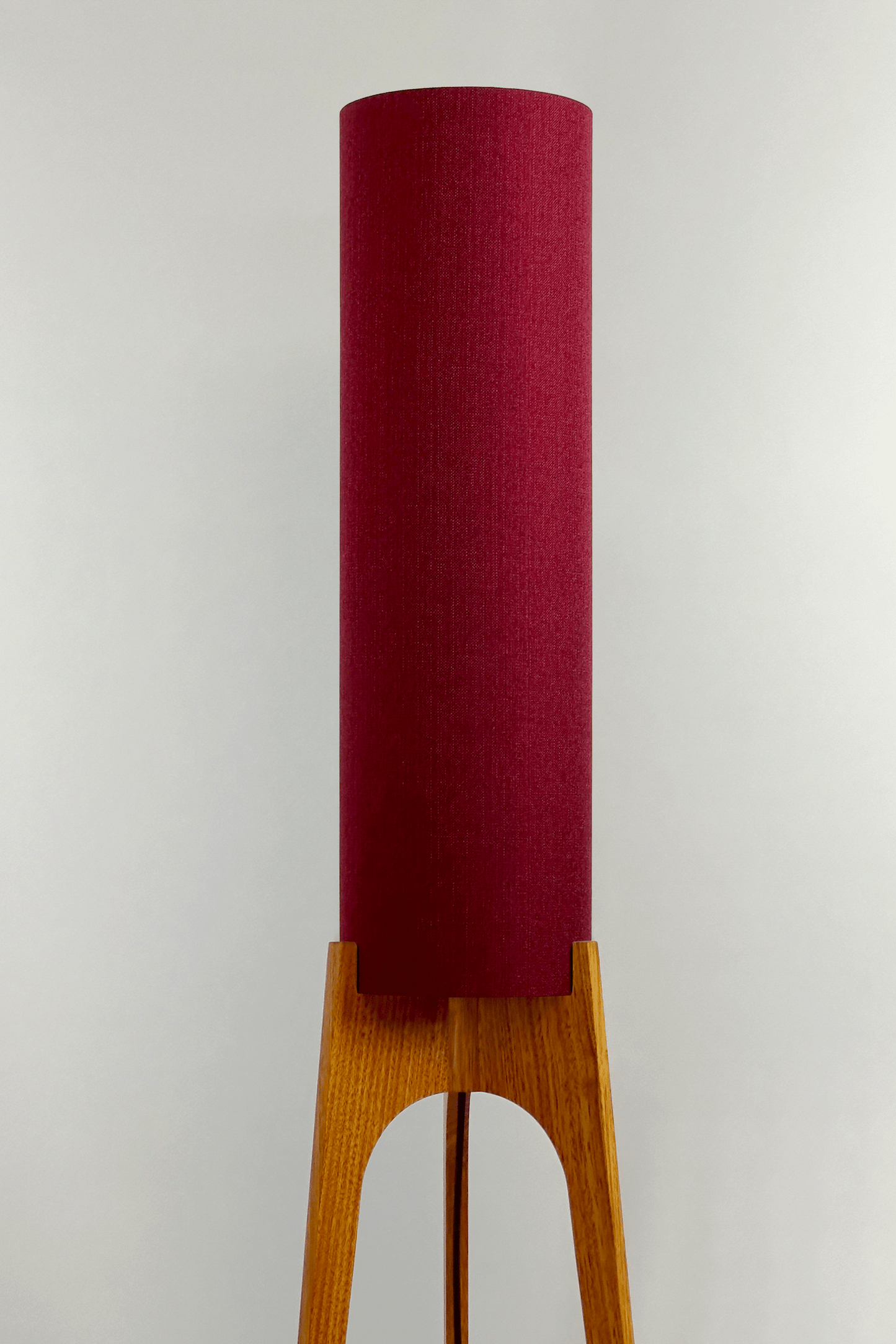 Wooden rocket floor lamp with a Burgundy cylindrical lampshade handmade from recycled fabric, on a neutral background
