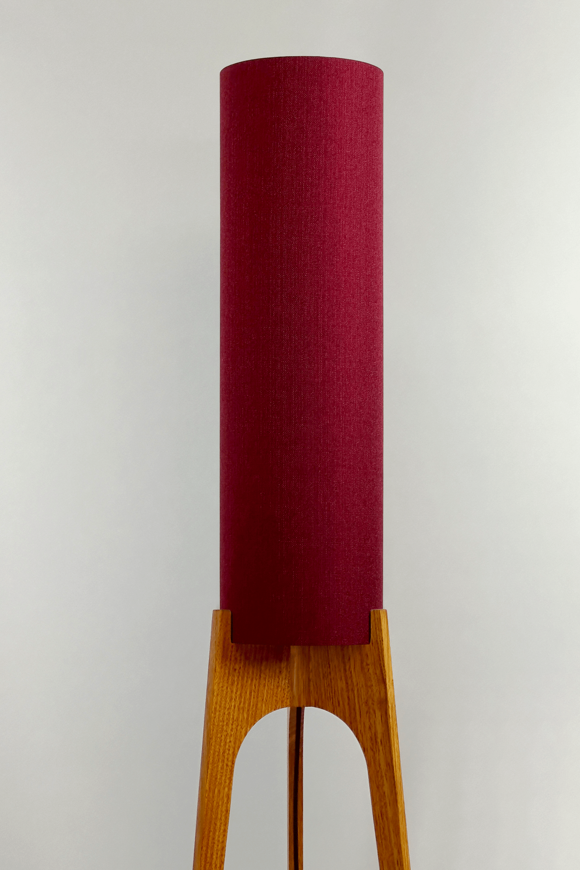 Wooden rocket floor lamp with a Burgundy cylindrical lampshade handmade from recycled fabric, on a neutral background