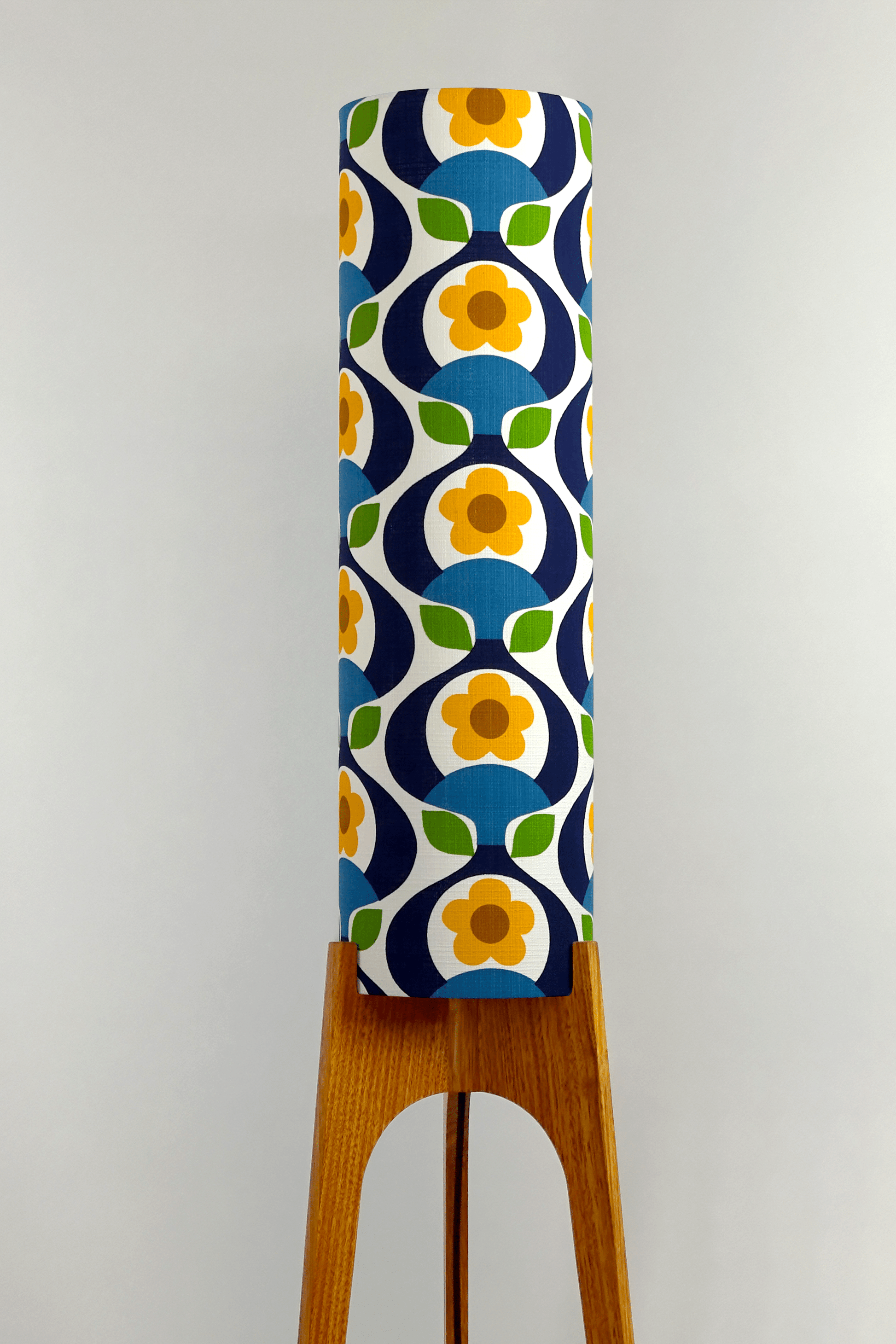 Wooden rocket floor lamp with a colourful geometric patterned lampshade handmade from authentic 70's vintage fabric on a plain background