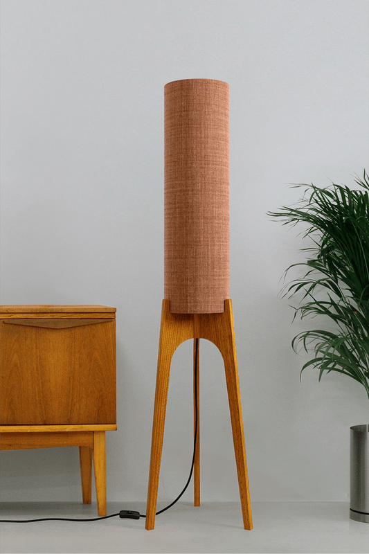 The Clay Archie Rocket Floor Lamp by Retro Duo, featuring a handcrafted wooden base and Clay cylindrical shade, styled beside a wooden cabinet and plant against a light grey background.