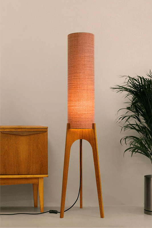 The Clay Archie Rocket Floor Lamp by Retro Duo, featuring a handcrafted wooden base and Clay cylindrical shade, styled beside a wooden cabinet and plant against a light grey background.