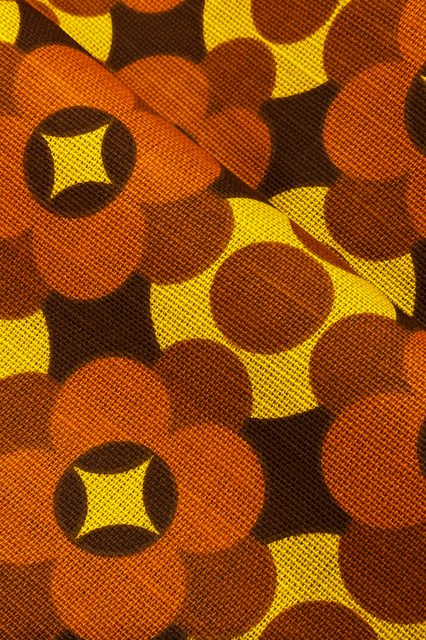 Close-up of Coco - 70's vintage fabric with a pattern of brown, yellow, and orange shapes.