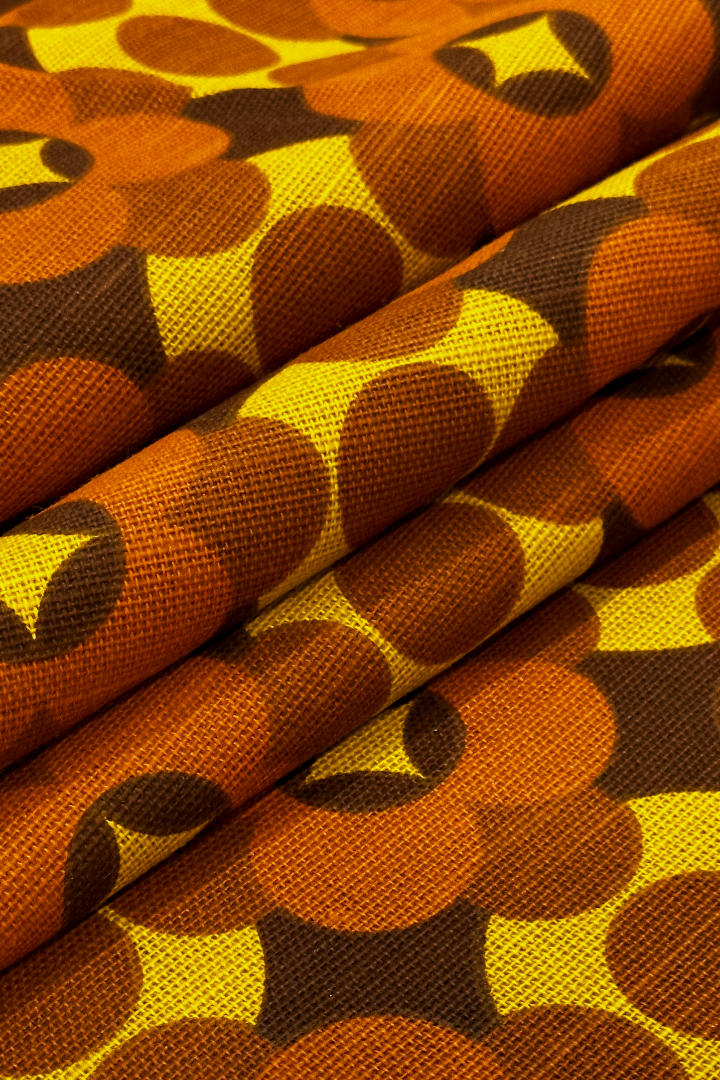 Close-up of Coco - 70's vintage fabric with a pattern of brown, yellow, and orange shapes.