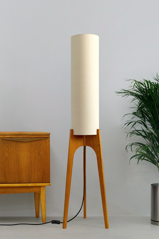 Cotton – Premium Linen Archie Rocket Floor Lamp with a beige shade next to a wooden cabinet and plant on a neutral background. Clean, airy, and effortlessly versatile, its soft tone brings calm and clarity to any space.