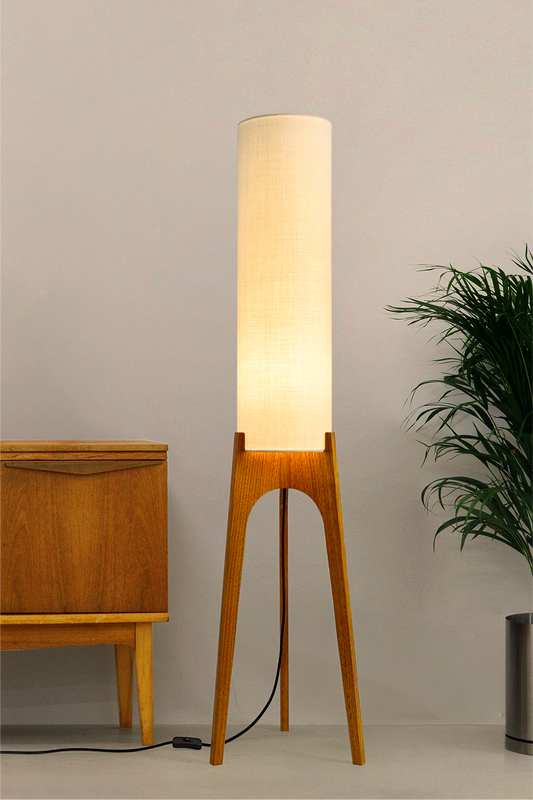 Cotton – Premium Linen Archie Rocket Floor Lamp with a beige shade next to a wooden cabinet and plant on a neutral background. Clean, airy, and effortlessly versatile, its soft tone brings calm and clarity to any space.