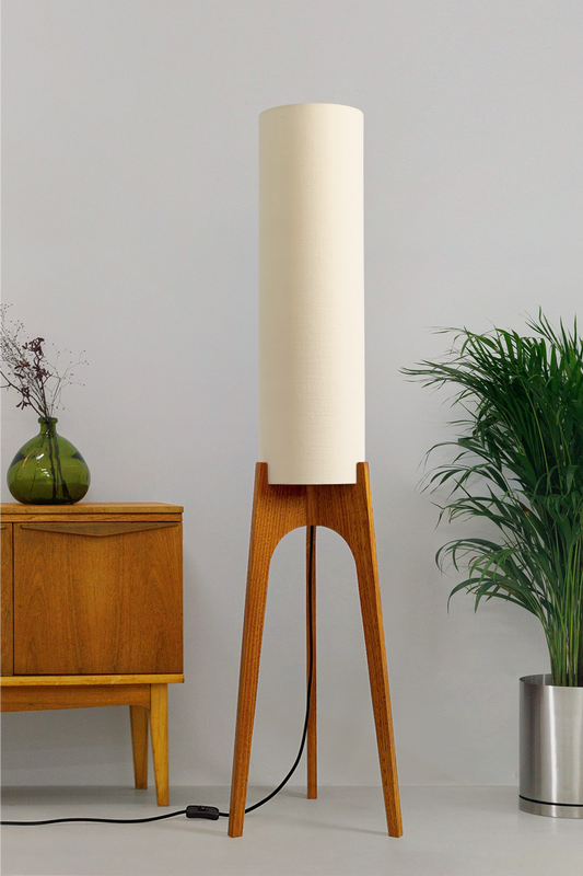 Cotton – Premium Linen Archie Rocket Floor Lamp with a beige shade next to a wooden cabinet and plant on a neutral background. Clean, airy, and effortlessly versatile, its soft tone brings calm and clarity to any space.