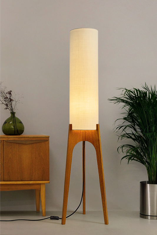 Cotton – Premium Linen Archie Rocket Floor Lamp with a beige shade next to a wooden cabinet and plant on a neutral background. Clean, airy, and effortlessly versatile, its soft tone brings calm and clarity to any space.