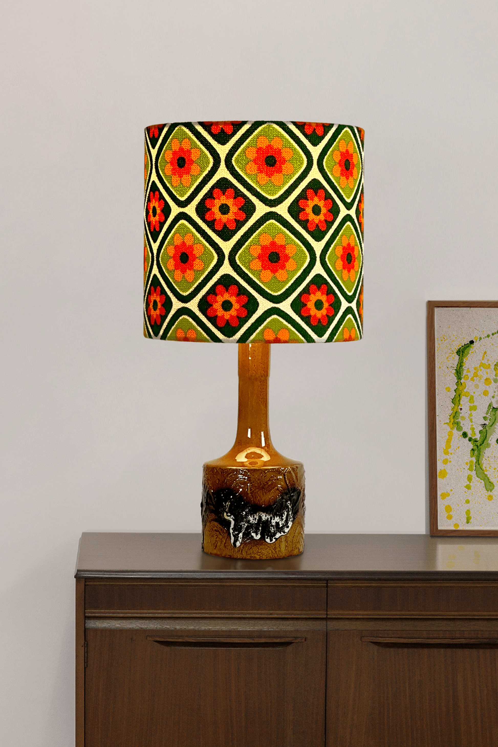 Emearld Bliss handmade lampshade with a colorful geometric pattern with a ceramic vintage lamp on a wooden cabinet.