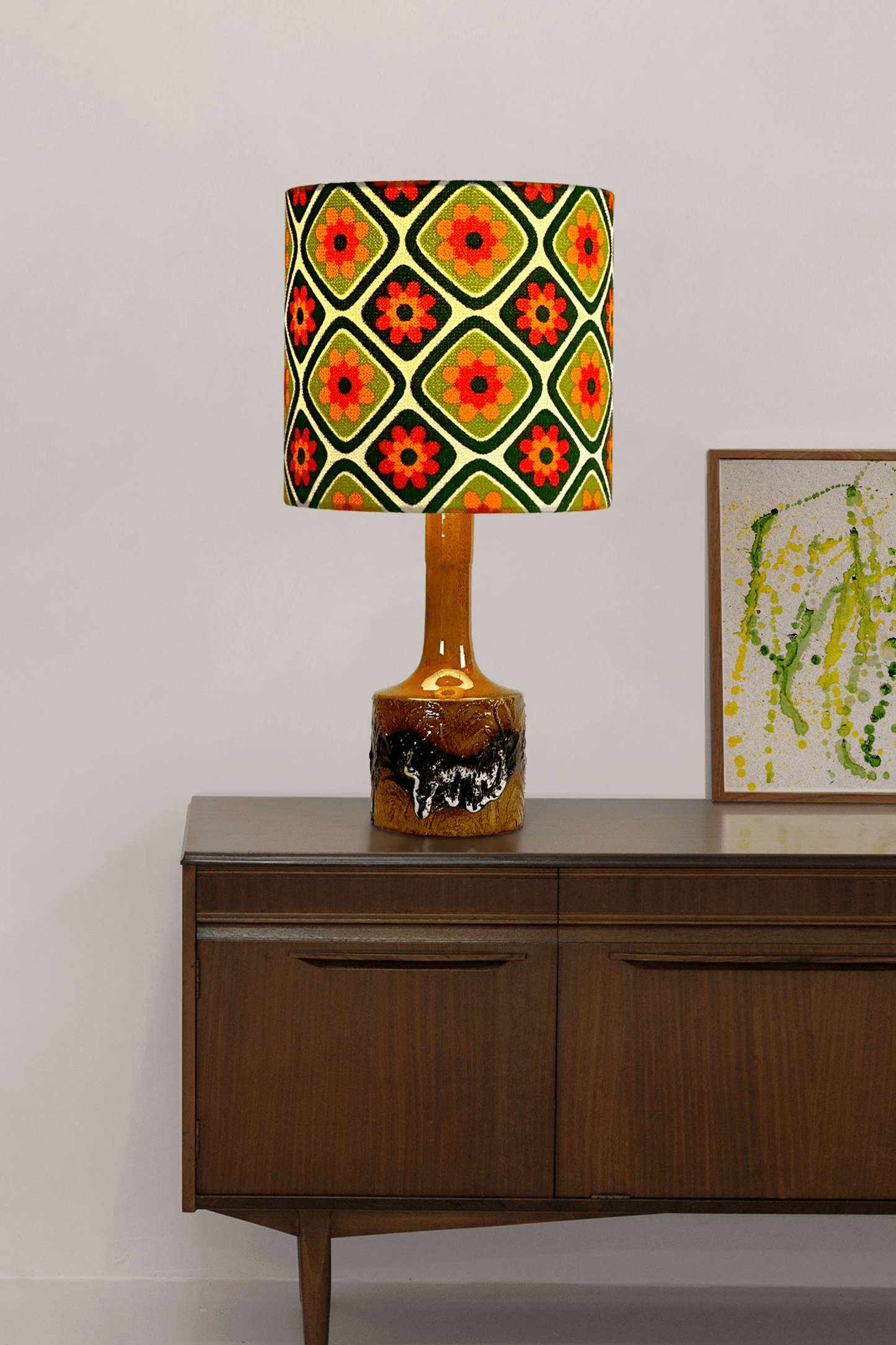 Decorative lamp with a colorful pattern on a wooden sideboard against a white wall.