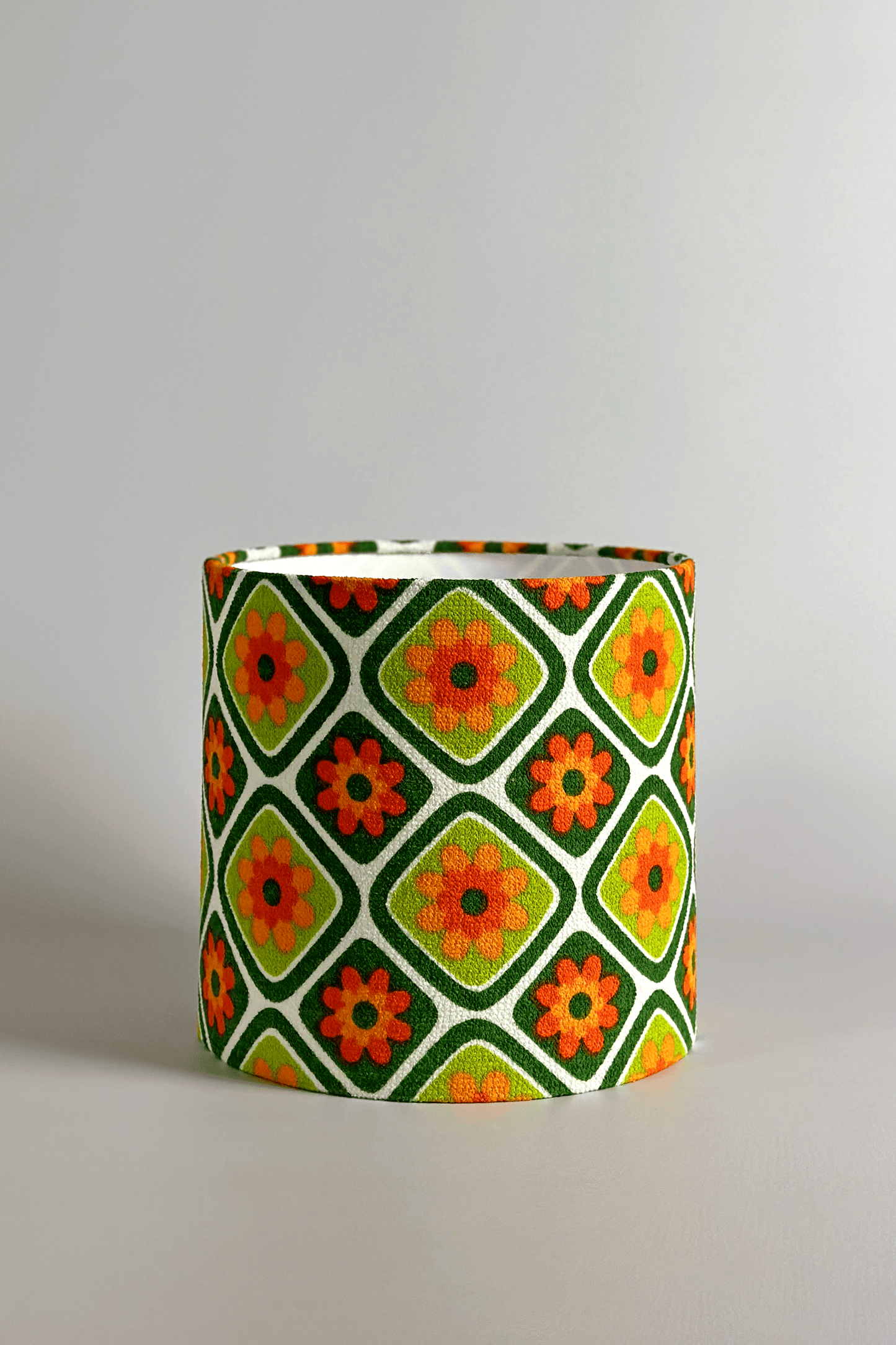 Cylindrical fabric lampshade with a geometric floral pattern on a plain background