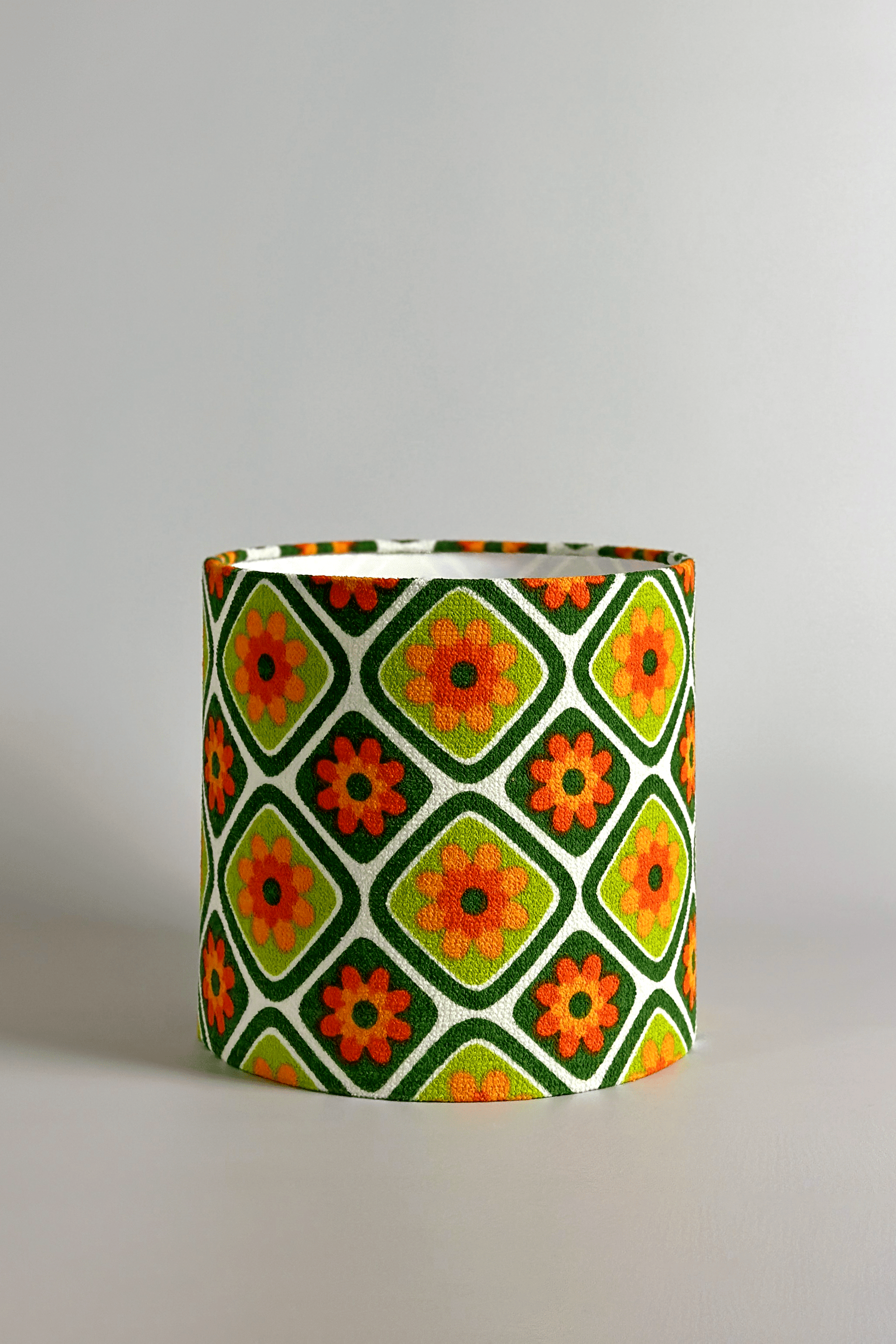 Cylindrical fabric lampshade with a geometric floral pattern on a plain background