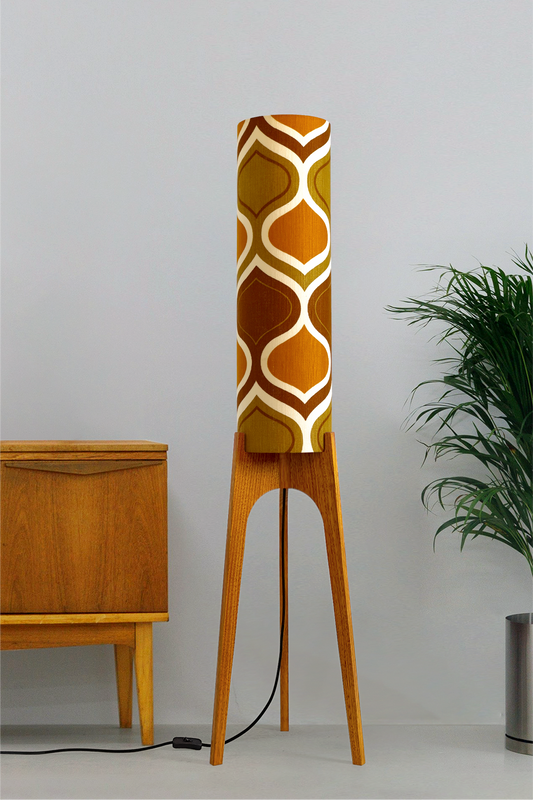 The Honey Mustard Archie Rocket Floor Lamp is a playful nod to the geometric patterns of the 1970s. Handcrafted from authentic vintage fabric and hardwood oak next to a wooden cabinet and plant.