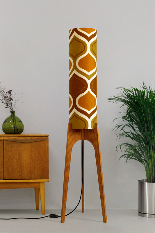 The Honey Mustard Archie Rocket Floor Lamp is a playful nod to the geometric patterns of the 1970s. Handcrafted from authentic vintage fabric and hardwood oak next to a wooden cabinet and plant.