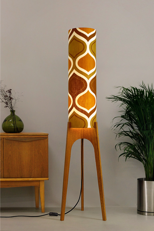 The Honey Mustard Archie Rocket Floor Lamp is a playful nod to the geometric patterns of the 1970s. Handcrafted from authentic vintage fabric and hardwood oak next to a wooden cabinet and plant.