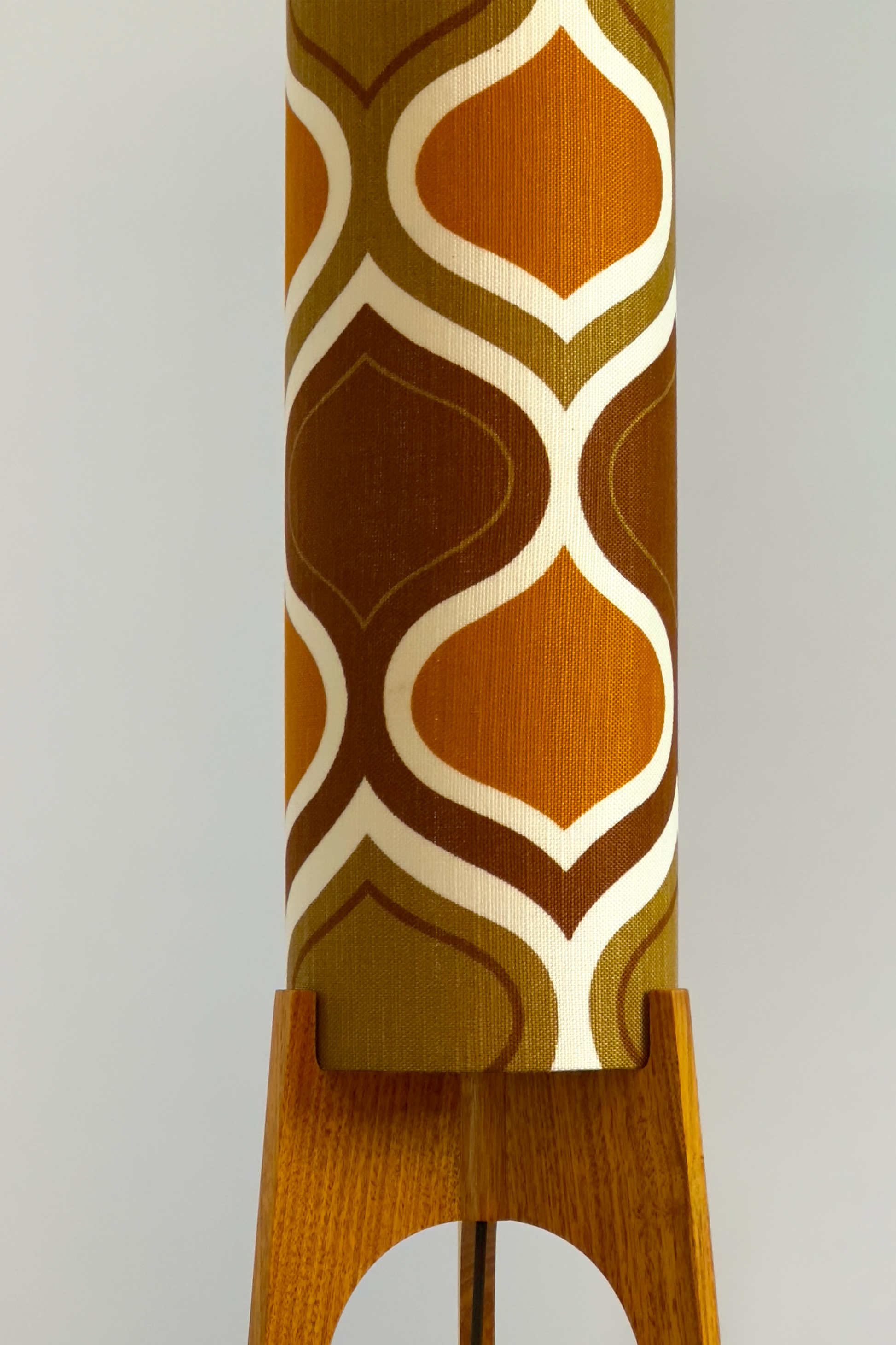 The Honey Mustard Archie Rocket Floor Lamp is a playful nod to the geometric patterns of the 1970s. Handcrafted from authentic vintage fabric and hardwood oak next to a wooden cabinet and plant.