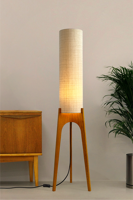 Ivory - Archie Rocket Floor Lamp handmade by Retro Duo. A soft, natural and timeless wooden floor lamp with a cylindrical shade in a room with a cabinet and a plant.