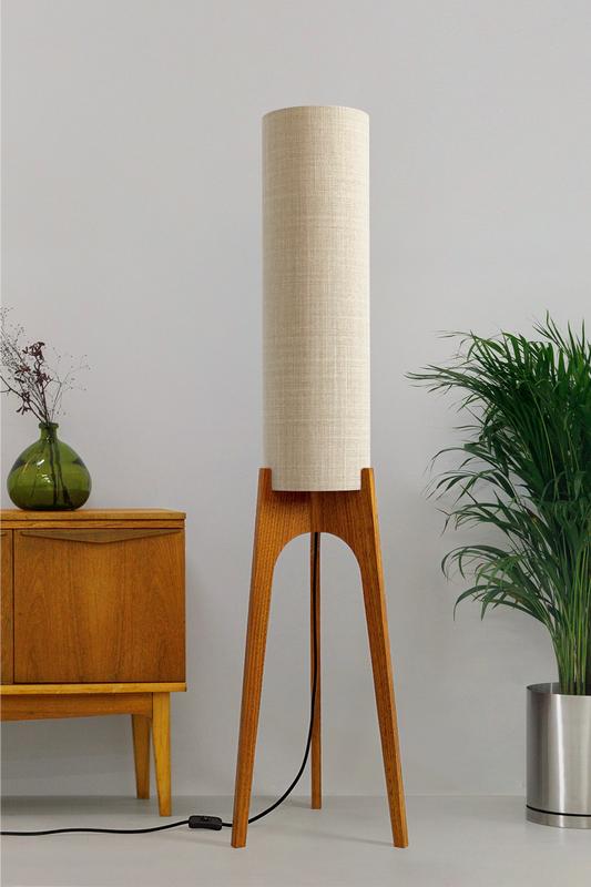 Ivory - Archie Rocket Floor Lamp handmade by Retro Duo. A soft, natural and timeless wooden floor lamp with a cylindrical shade in a room with a cabinet and a plant.