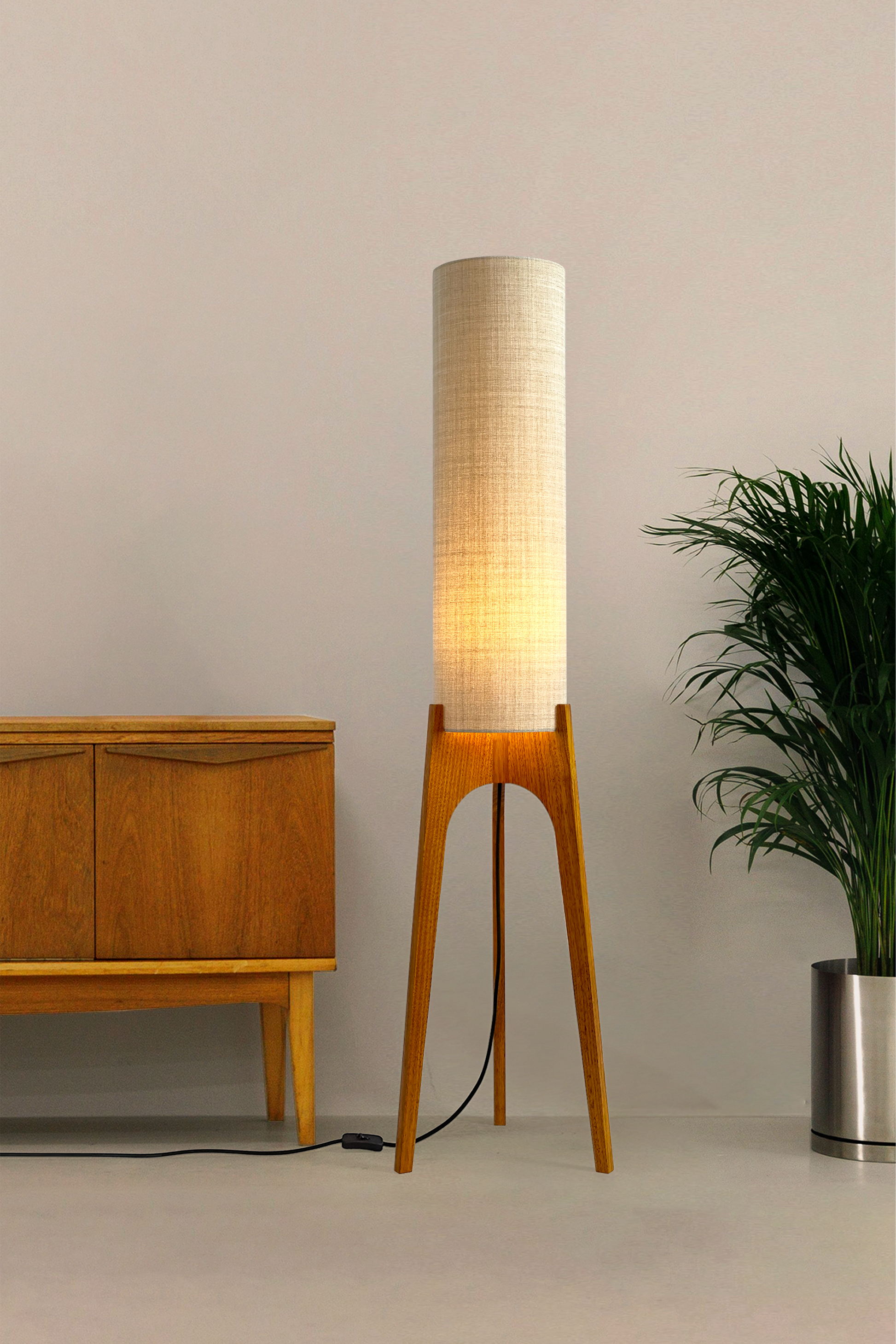 Ivory - Archie Rocket Floor Lamp handmade by Retro Duo. A soft, natural and timeless wooden floor lamp with a cylindrical shade in a room with a cabinet and a plant.