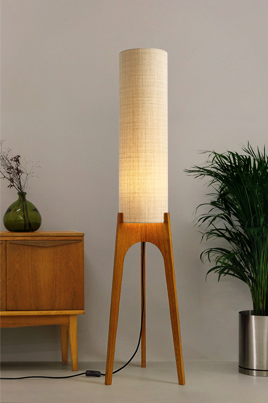 Ivory - Archie Rocket Floor Lamp handmade by Retro Duo. A soft, natural and timeless wooden floor lamp with a cylindrical shade in a room with a cabinet and a plant.