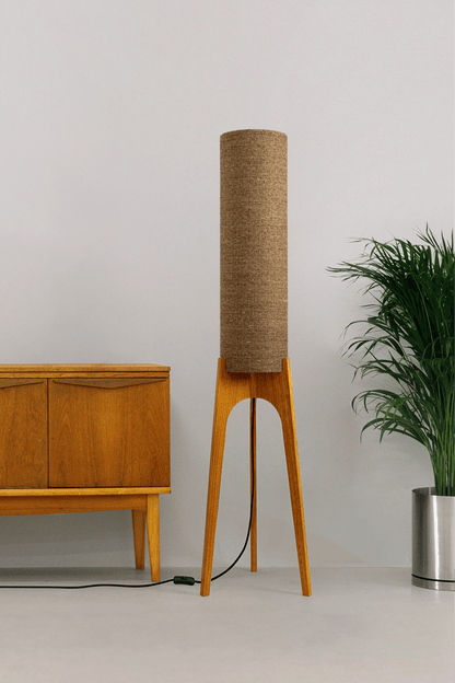 a handmade Rocket Floor Lamp with a woven lampshade in brown and a wooden lamp base in a mid-century room setting