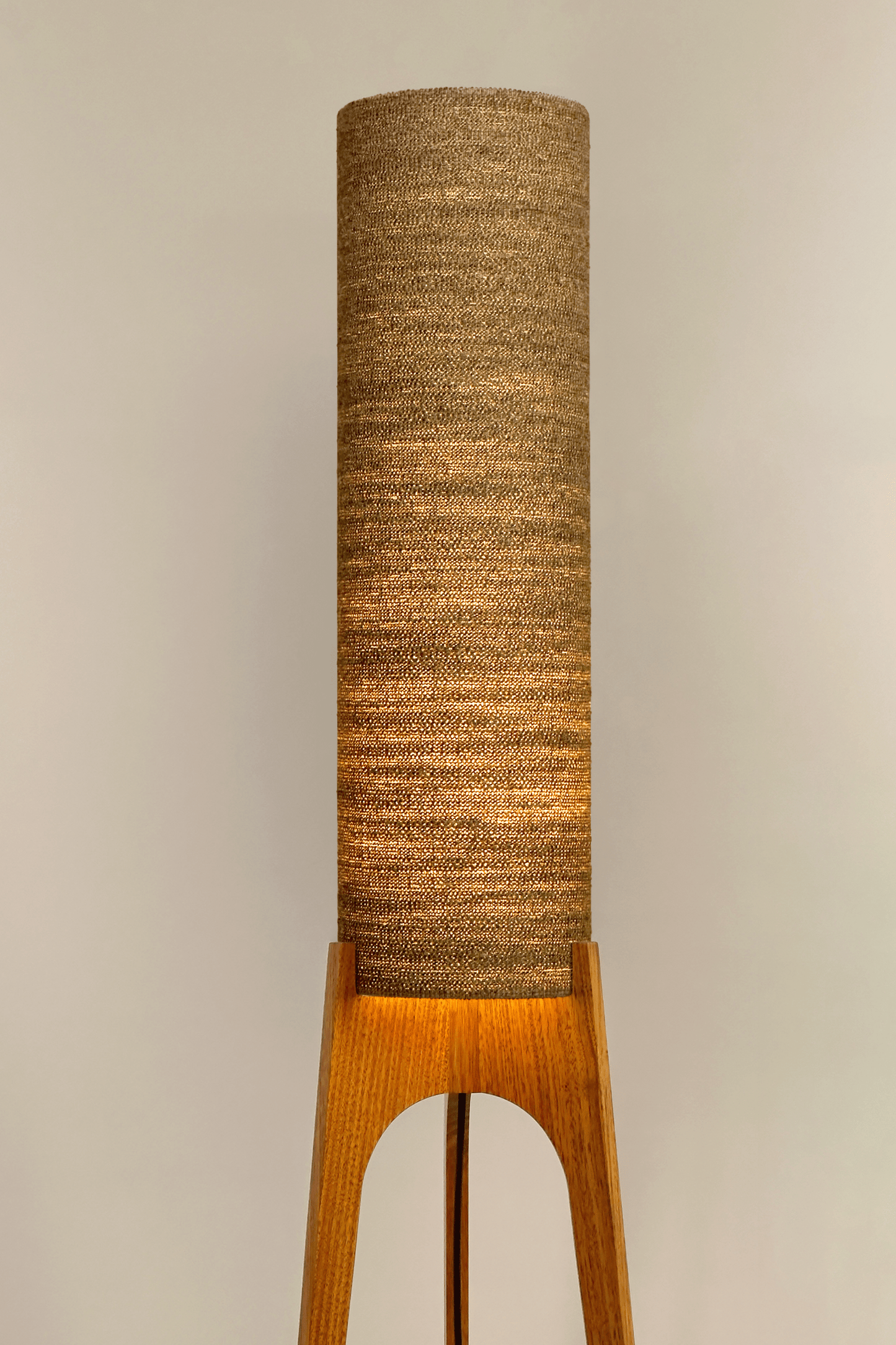 a handmade Rocket Floor Lamp with a woven lampshade in brown and a wooden lamp base in a mid-century room setting