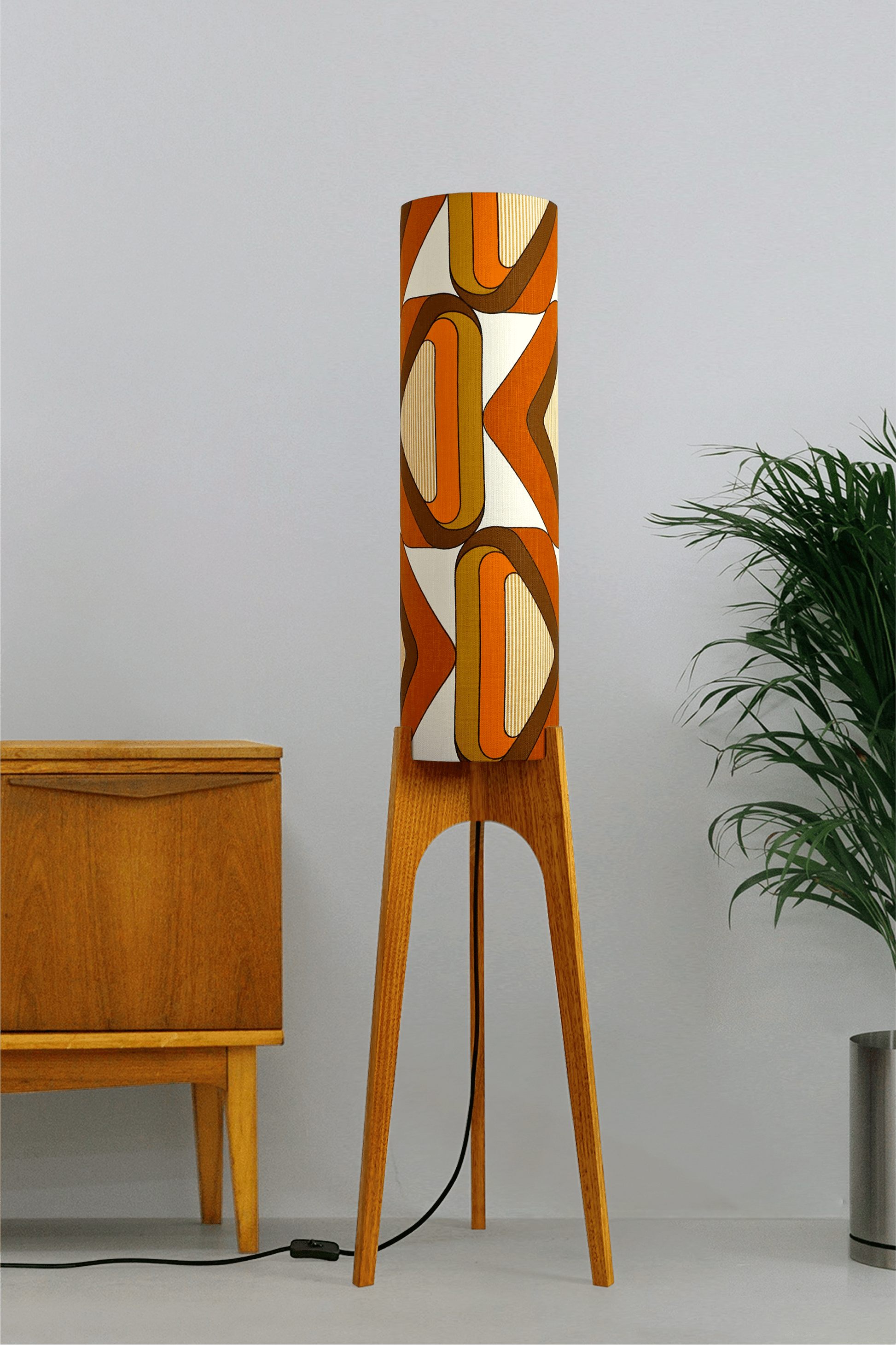 Wooden rocket floor lamp with a handmade lampshade in vintage geometric patterned fabric on a plain background