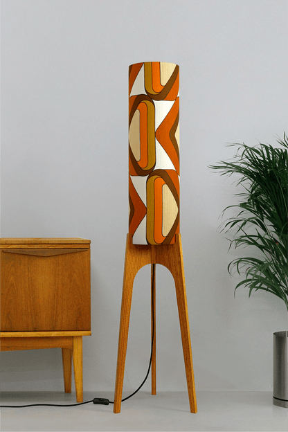 Wooden rocket floor lamp with a handmade lampshade in vintage geometric patterned fabric on a plain background