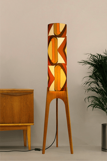 Wooden rocket floor lamp with a handmade lampshade in vintage geometric patterned fabric on a plain background