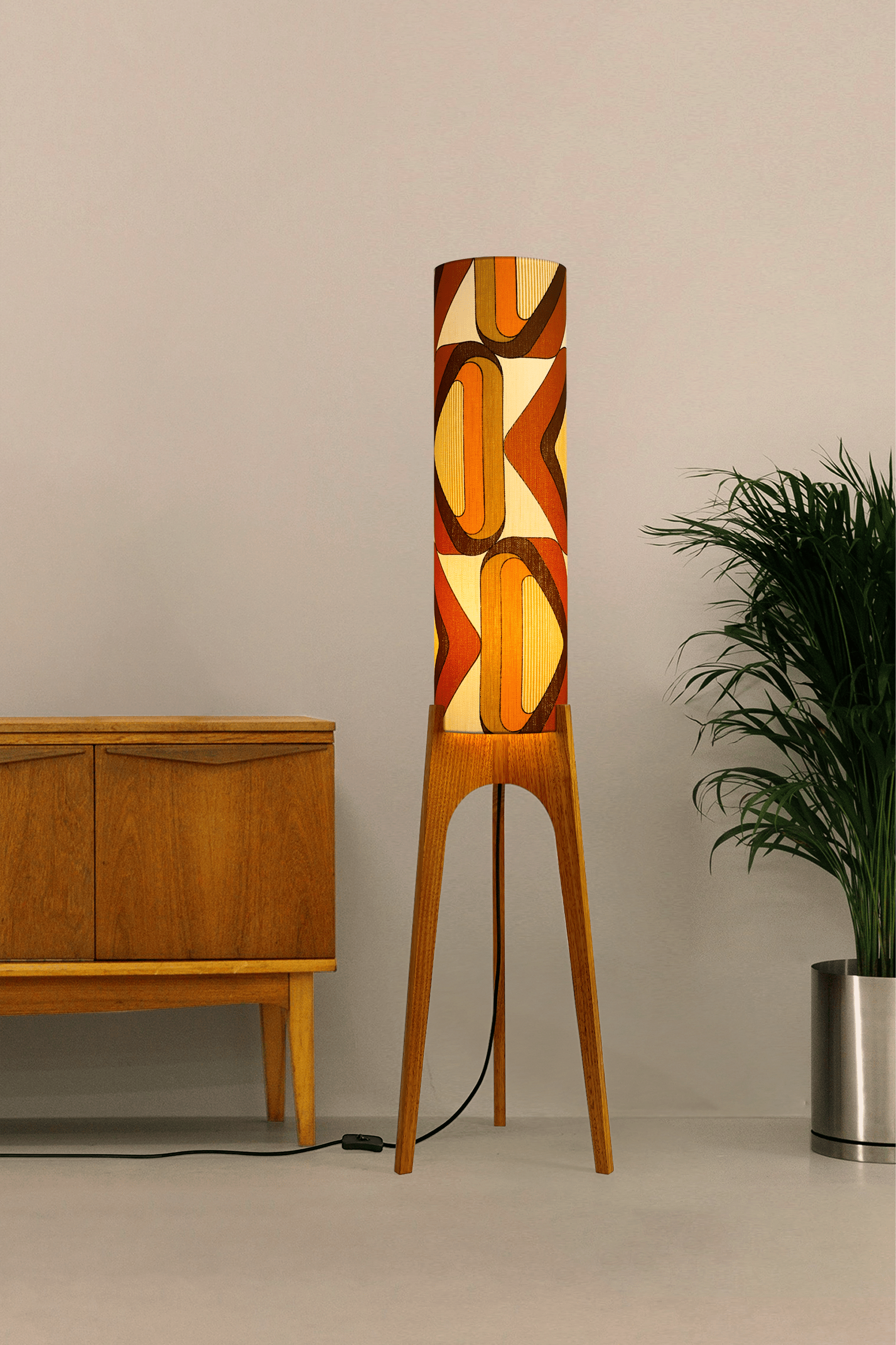 Wooden rocket floor lamp with a handmade lampshade in vintage geometric patterned fabric on a plain background
