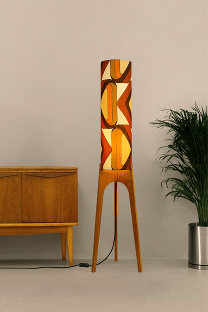 Wooden rocket floor lamp with a handmade lampshade in vintage geometric patterned fabric on a plain background
