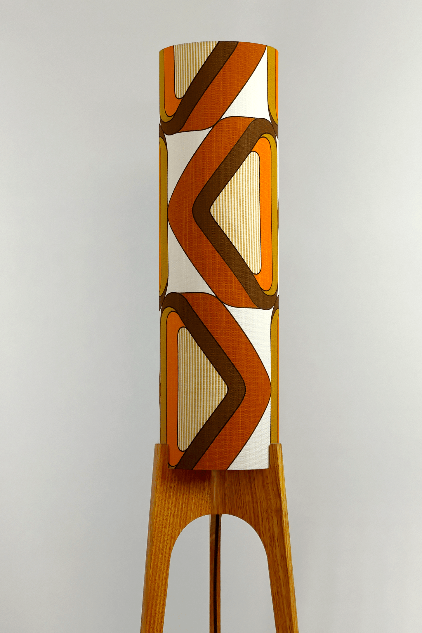 Wooden rocket floor lamp with a handmade lampshade in vintage geometric patterned fabric on a plain background