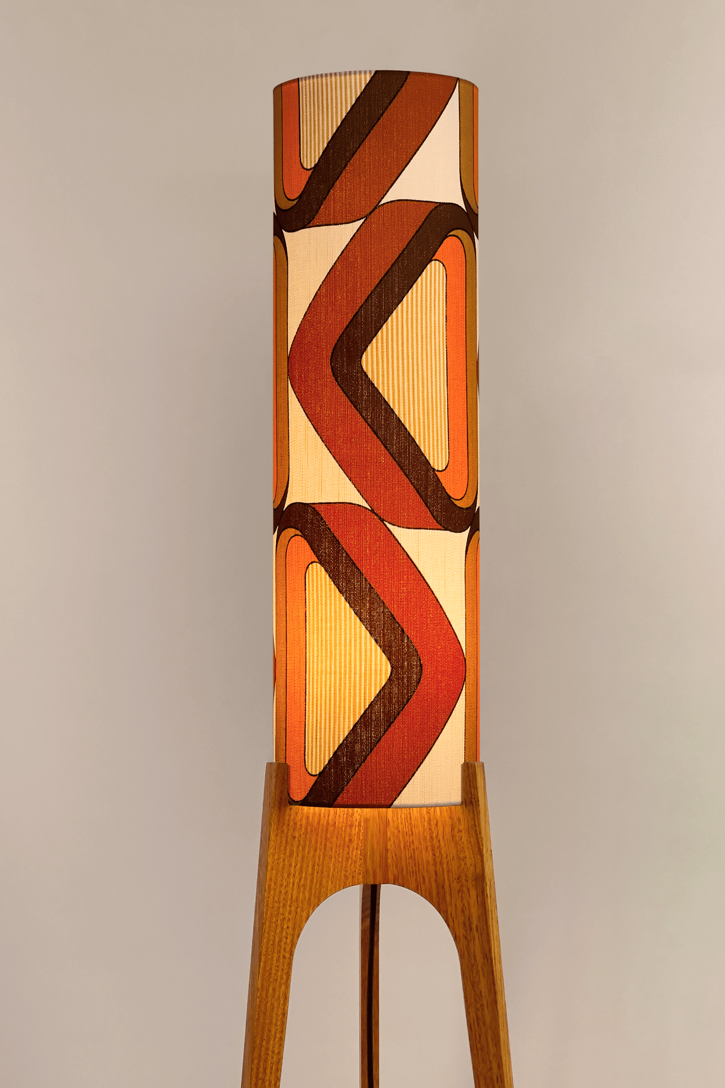 Wooden rocket floor lamp with a handmade lampshade in vintage geometric patterned fabric on a plain background