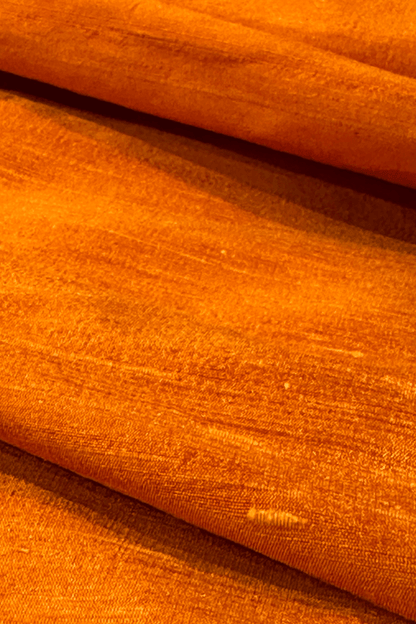 Close-up of orange raw silk fabric with visible texture