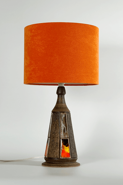 Table lamp with an orange shade and decorative base on a white background