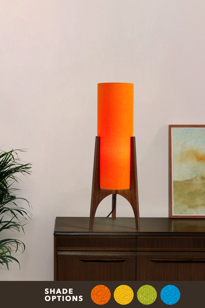 Orange Archie Rocket Table lamp with a handmade wooden base and recycled fabric shade on a dark surface against a white wall.