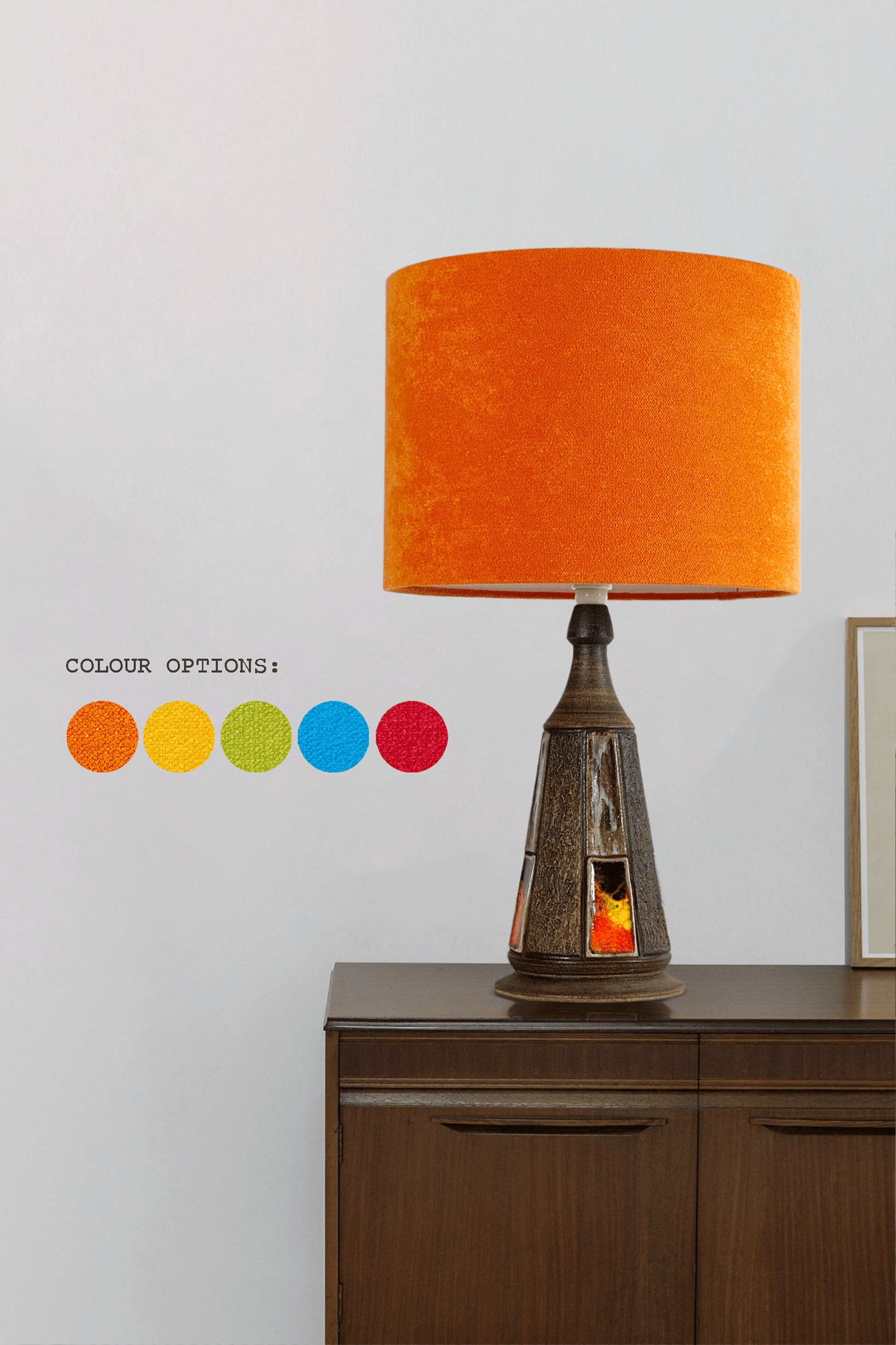 Table lamp with orange shade on a wooden cabinet against a white wall, with color option swatches displayed.