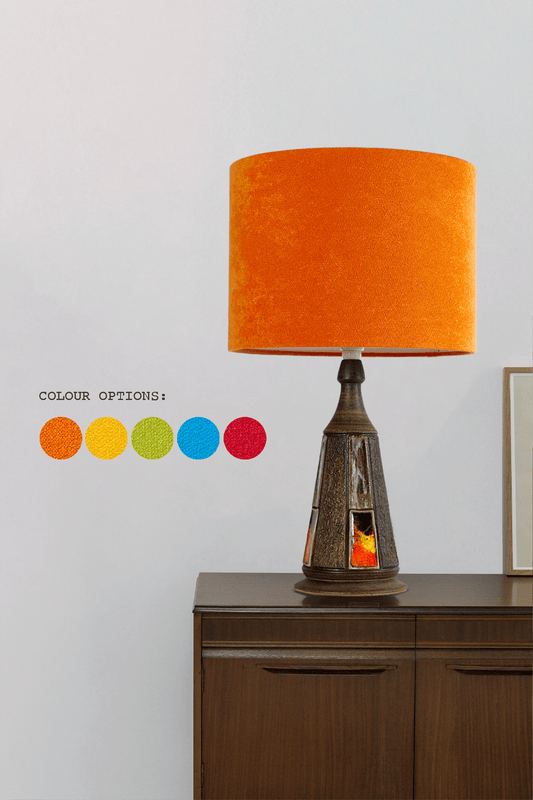 Table lamp with orange shade on a wooden cabinet against a white wall, with color option swatches displayed.