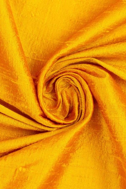 Close-up of saffron yellow raw silk fabric with a swirl pattern